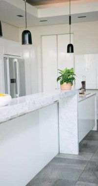 Dikey video: Mermer tezgahlı modern mutfak ve meyve kasesi taze atmosfer yaratıyor. Çağdaş, iç mekan, tasarım, lüks, minimalizm, dekor