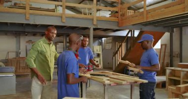 Afrikalı Amerikan takımı tezgahta toplanırken eğitmen de çıkış yolunu gösteriyor. El işçiliği, takım çalışması, sanayi, akıl hocalığı, hassasiyet, inşaat, eğitim