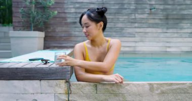 Arka bahçede havuzda dinlenen, limonlu suyu yudumlayan, güneş gözlüğü takan bir kadın. Boş zaman, yaz, açık hava, yaşam tarzı, susuzluk, sükunet, minimalist