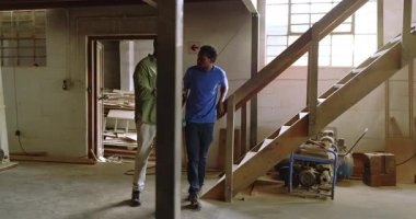 Afro-Amerikalı iş arkadaşları alışveriş için merdivenlerden iniyor, bankları işaret ediyor, tablet kullanarak toplanıyorlar. Sanatçılık, işbirliği, sanayi, çalışma alanı, tasarım, ahşap işçiliği, akıl hocalığı