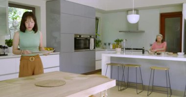 Çinli anne ve kız kaseleri karıştırıyor tabakları koyuyor meyve suyunu masaya döküyor. Aile, evcil, rahat, yaşam tarzı, dürüstlük, samimiyet, birliktelik