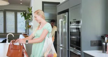 Çeşitli çiftler mutfağa çantalarla ve çantalarla giriyor. Yemek hazırlamak için meyve ve kavanozları açıyorlar. Modern, yaşam tarzı, minimalist, yerli, sağIık, işbirliği, canlı