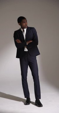 Dikey video: Profesyonel moda stüdyosunda poz veren şık takım elbiseli kendine güvenen adam. stil, zarafet, erkek giyim, fotoğraf çekimi, modellik, özgüven.