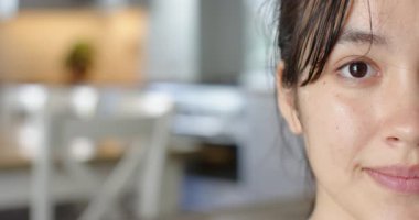 Tarafsız bir yüz ifadesini elinde tutan Asyalı bir kadın. Mutfaktaki kameraya gülümseyip göz kırpıyor. Portre, ifade, neşe, mutluluk, sıcaklık, samimiyet, yaşam tarzı