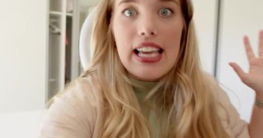 Akıllı telefonu kaldırdıktan sonra, kadın yatak odasında yüzük ışığı altında kolunu uzatarak seyirciyi selamlıyor. Stüdyo, vloglama, portre, teknoloji, iletişim, yaşam tarzı, neşeli