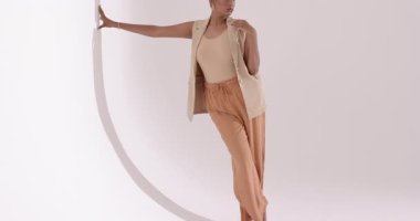 Stüdyoya girmek Hintli kadının dairesel kemer destekli poz vermesini tetikliyor, ceketi çekim sırasında ayarlıyor. Moda, zarafet, minimalizm, güzellik, portre, stüdyo, sofistike