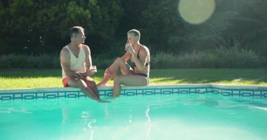 Orta yaşlı bir çift arka bahçedeki havuz kenarına varıyor, bardakları tokuşturuyor, konuşuyor, buz küpü uzatıyorlar. Boş zaman, rahatlama, dostluk, açık hava, yaz, yaşam tarzı, canlı