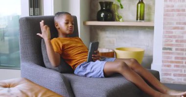 Afro-Amerikalı çocuk telefon sürprizi gördü oturma odasında sevinçle dikildi. Teknoloji, eğlence, rahatlama, modern, gençlik, merak, mutluluk