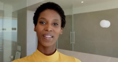 Zarif bir selamlama ile açılışı yapan Afro-Amerikalı kadın banyo iç ve balkon manzarasını tanıtıyor. Lüks, sağlık, zarafet, konfor, doğal ışık, sükunet, modern tasarım.