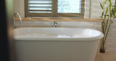 Doldurulduktan sonra, sabunlu köpük yer değiştiriyor, pencerenin altındaki küvet suyunda dalgalanmalar oluyor. Lüks, rahatlama, minimalist, spa, sükunet, iç mekan, sükunet