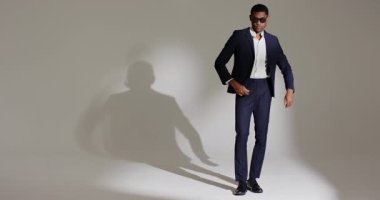 Afrika kökenli Amerikalı erkek model moda çekimine giriyor, takım elbise ve güneş gözlüğü fotokopi alanına giriyor. Profesyonel, stil, monokrom, zarafet, güven, poz, erkek