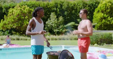 Limonata bardağını kaldırdıktan sonra, çeşitli erkek arkadaşlar havuz tıkırdatarak ızgara köfte pişiriyor. Barbekü, eğlence, açık hava, yaz, rahatlama, arkadaşlık, coşku