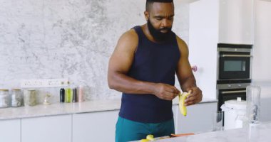 Afro-Amerikalı adam modern mutfakta yemek pişiriyor, meyve, akıllı telefon ve blender arasında limon tutuyor. Aşçılık, aşçılık, mutfak, hayat dolu, hazırlık, taze, sağlıklı