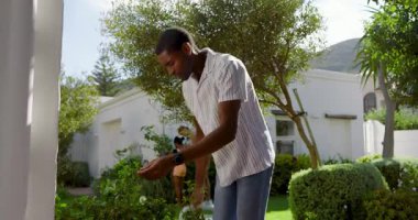 Arka bahçede bahçe işleri, kadın yanında çocukla yürürken erkek. Açık hava, çeşitli aileler, boş zaman, bahçecilik, kaynaşma, ebeveynlik