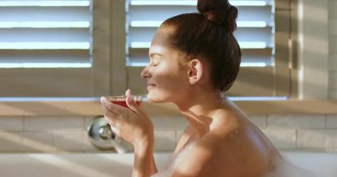 Sabah ışığı panjurların önünden geçiyor. Banyoda çay fincanından yudumlayan kadına rehberlik ediyor. Kopya uzayı. Huzur, rahatlama, sağIık, ortam, doğal ışık, çağdaş, kişisel bakım.