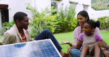 Bahçede eğlenen çeşitli aileler bahçede güneş enerjisini öğreniyorlar. Sürdürülebilirlik, çevre, teknoloji, yenilenebilir, eğitim, takım çalışması