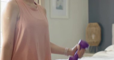 Asyalı kadın mor dambıllara uzanıyor ve yatak odasında güç eğitimi için kıvrılıyor. Fitness, kuvvet, ev çalışması, sağlık, dengeli yaşam tarzı, kararlılık, modern