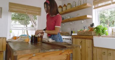 Mutfakta elinde muz tutan, gülümseyen ve evde taze meyve sepeti hazırlayan bir kadın. Sağlıklı, yemek, beslenme, sağlık, yaşam tarzı, tazelik.