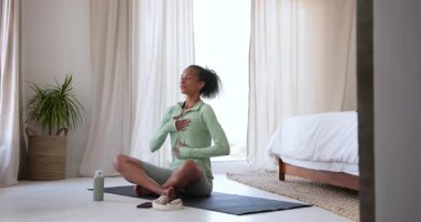 Yeşil giysili bir kadın evde yoga minderinde su içiyor, antrenmandan sonra dinleniyor. Zindelik, sağlık, su, egzersiz, yaşam tarzı, rahatlama.