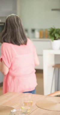 Dikey video: Anne ve kızı modern mutfakta birlikte yemek pişiriyor, kaliteli zaman geçiriyorlar. Aile, bağlılık, yaşam tarzı, aşçılık, aile içi, mutluluk