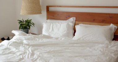 Yatak odası dağınık ve sabah ışığı penceresinden içeri akıyor. Hygge, iç mekan, rahatlama, sükunet, konfor, dekor