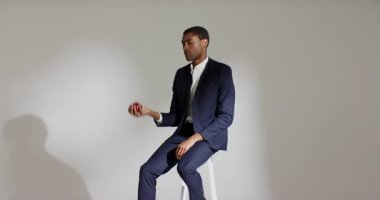 Kırmızı elma tutan, Afrika kökenli Amerikalı bir adam stüdyoda elma atıp yakalıyor, meyveleri denetliyor. Portre, zarafet, farkındalık, sofistike, denge, minimalizm, sağlık