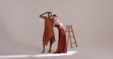 Hintli ve Çinli kadın modeller omuzlarına dokunuyor, stüdyoda merdiven çekerek poz veriyorlar. Zarafet, bağlantı, işbirliği, uyum, minimalist, akıcılık, moda