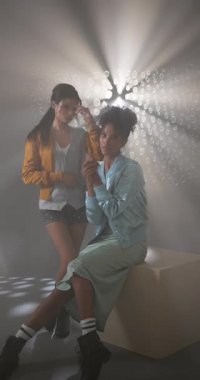 Dikey video: Yaratıcı stüdyo aydınlatma efektlerinden hoşlanan şık grunge elbiseli arkadaşlar. Moda, alternatif, grup