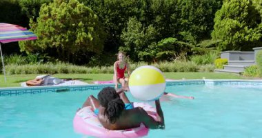 Çeşitli arkadaşlar arka bahçedeki havuzda voleybol oynuyorlar. Eğlence olsun diye top atıyorlar. Açık hava, eğlence, eğlence, coşku, yaz, su, arkadaşlık.