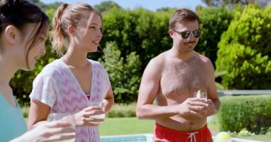 Gömleksiz adam jest yapıyor arkadaşlara kıvılcım saçıyor hamburger pişiriyor, havuz başında mısır şişleri pişiriyor. Rahatlama, açık havada yaşam, rahatlama, sosyalleşme, yaz zamanı, hayat dolu, yaşam tarzı