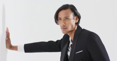 Asyalı erkek manken, beyaz duvara avuç içi bastırıp moda pozu veriyor. Minimalist, zarif, duruş, dinamik, profesyonellik, monokrom, tarz