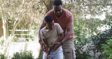 Afrikalı Amerikalı baba ve oğul golf kulübünü öğreniyorlar. Avluda sallanıyorlar. Kavrama ve yumruk tokuşturmadan sonra. Aile, akıl hocalığı, açık hava, eğitim, boş zaman, kaynaşma, aktivite