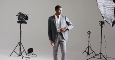 Afrikalı Amerikalı erkek model klapaları ayarlıyor, stüdyo ışıklarını kontrol ediyor, çekimlere hazırlanıyor. Profesyonel, minimalist, düşünceli, moda, ticari, tarz, lüks