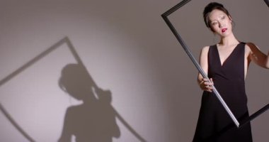 Sahne ışıkları, Asyalı kadını yönlendiriyor. Stüdyoda geniş çerçeveyi çapraz kaydırıyor. Kopya uzayı. Siluet, minimalizm, zarafet, kompozisyon, sanatsal, moda, kontrast