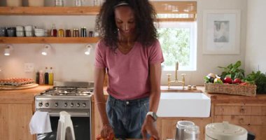 Mutfakta taze meyve salatası hazırlayan bir kadın, evinde mutlu bir şekilde gülümsüyor. Aşçılık, aşçılık, sağlıklı yaşam tarzı, beslenme, mutluluk, yerli