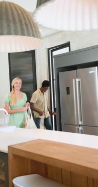 Dikey video: Modern mutfakta paketleri açmak, çiftlerin gülümsemesi ve birlikte zaman geçirmesi. Aşçılık, ev, yerli, ilişki, mutluluk, yaşam tarzı