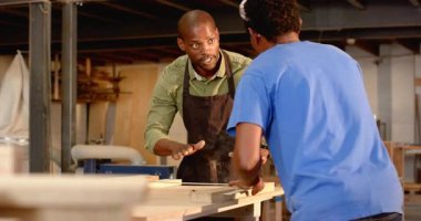 Afrika kökenli Amerikalı erkek akıl hocası kesim için mezura ile çırak işaretliyor. İşçilik, akıl hocalığı, eğitim, marangozluk, içişleri, sanayi, odaklanma