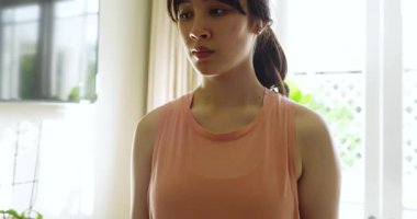 Prompted by tracker alert, Asian woman lifting dumbbell in bedroom wearing sportswear for fitness. Fitness, strength, workout, health, determination, mobility, lifestyle