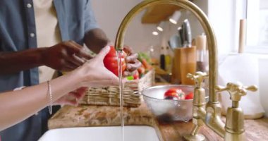 Mutfakta taze sebzeleri yıkamak, çeşitli çiftler evde birlikte sağlıklı yemekler hazırlamak. Aşçılık, beslenme, ev, yaşam tarzı, yerli, malzeme