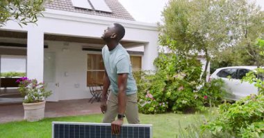 Adam bahçeye güneş paneli kuruyor, gökyüzüne bakıyor. Yenilenebilir, güneş enerjisi, sürdürülebilir, kurulum, çevre, açık hava