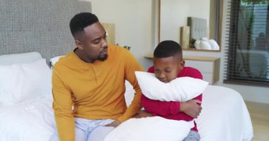 Afro-Amerikalı baba oğlunun beyaz yastığa sarılıp güven verici bir sarılma teklif etmesine tepki veriyor. Rahatlık, bağ, destek, sıcaklık, şefkat, beslenme, duygusal