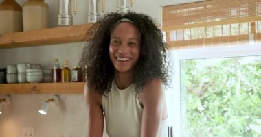 Mutfakta gülümseyen, evinde dinlenen bir kadın. Rahatlama, mutluluk, ifade, yemek pişirme, yaşam tarzı, evcil