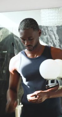 Dikey video: Adam banyo aynasında tımar ediliyor, görüntüyü odaklanmış ifadeyle ayarlıyor. Kişisel bakım, hijyen, kibir, konsantrasyon, yaşam tarzı, sakal.