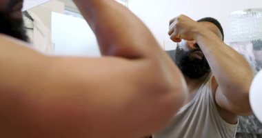 Afro-Amerikalı bir adam banyoda jilet ve aynayla doğal ışık altında kendini tımar ediyor. Tımar, yansıtma, kişisel bakım, kendini geliştirme, odaklanma, banyo, yaşam tarzı