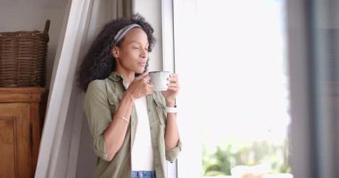 Kadın evde kahve içiyor, rahatlıyor ve dışarı bakıyor, fotokopi çekiyor. Rahatlama, yaşam tarzı, sabah, rahat, içecek, tefekkür