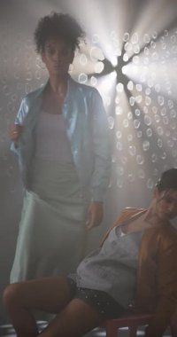 Dikey video: Huysuz, sanatsal stüdyo ışıklandırmasında kendine güvenen iki şık şahıs. Moda, tarz, portre, özgüven, cazibe, zarafet