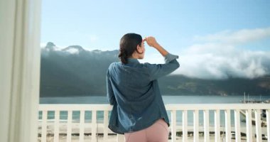 Balkondan okyanus manzarasını seven kadın kot ceket ve tayt giyiyor, fotokopi odası. Rahatlama, seyahat, moda, dinginlik, rahatlık, doğa