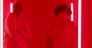 Afrikalı Amerikalı erkek arkadaşlar kırmızı ışıklı stüdyoda yumruk tokuşturuyor ve LED tüplerle çekim için poz veriyorlar. Arkadaşlık, işbirliği, kentsel, modern, canlı, gündelik, anlamlı