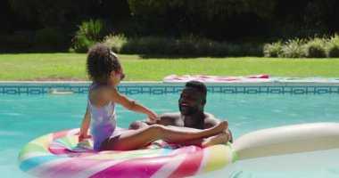 Afrika kökenli Amerikalı baba ve kız şekerler havuzda yüzüyor suya dokunduktan sonra gülüyorlar. Aile, eğlence, eğlence, canlı, samimi, açık hava, kaynaşma.