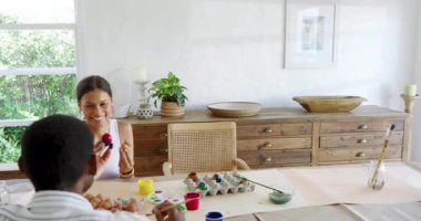 Tavşan kulağı takan genç bir kız evde çeşitli ailelerle paskalya yumurtası boyuyor. tatil, kutlama, çocuk, yaratıcılık, zanaat, renkli